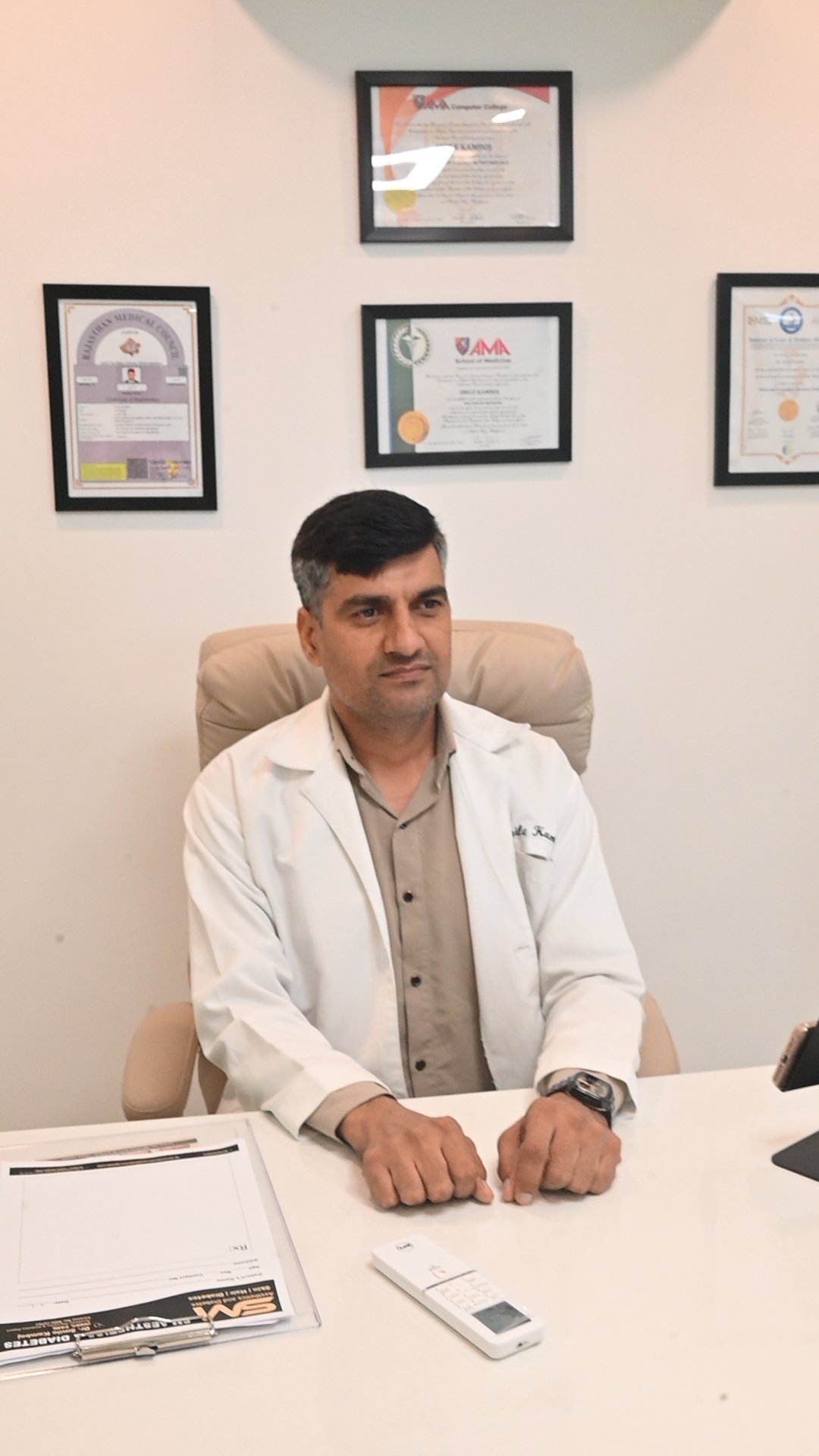A K7 Homecare doctor at his desk, with medical qualifications and certifications on display